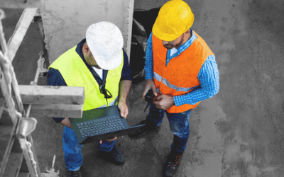 Construction team reviewing document control data on laptop at job site