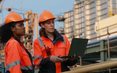 Construction team members managing complex construction documents on laptop